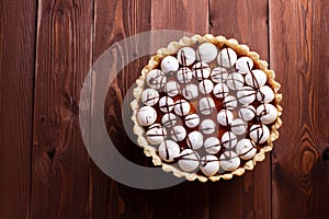 Vegan lemon tart decorated with Meringue kisses made from aquafaba, top view flatlay on brown wooden board with copy space