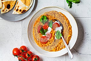 Vegan lentil soup with cilantro and tomato. Dal soup with tomatoes, top view. Indian cuisine concept