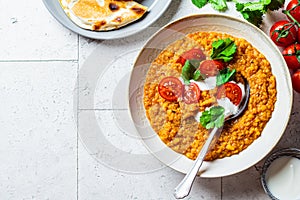 Vegan lentil soup with cilantro and tomato. Dal soup with tomatoes, top view. Indian cuisine concept