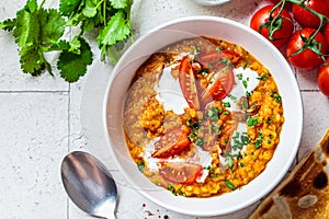 Vegan lentil soup with cilantro and tomato. Dal soup with tomatoes, top view. Indian cuisine concept