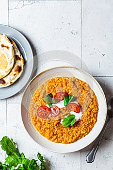 Vegan lentil soup with cilantro and tomato. Dal soup with tomatoes, top view. Indian cuisine concept