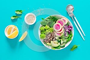 Vegan lunch bowl with quinoa, cucumber, green peas, radish, romanesco and red cabbage, avocado, spinach and arugula salad, healthy