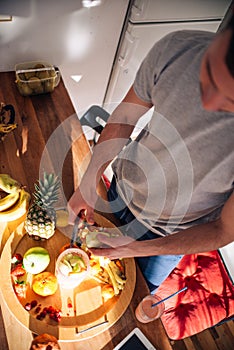 Vegan man in his 20`s has a morning preparation of a smoothie while looking at a recipe on his tablet