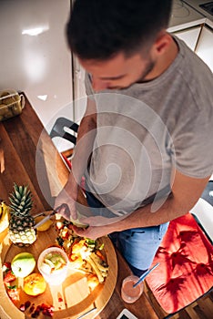 Vegan man in his 20`s has a morning preparation of a smoothie while looking at a recipe on his tablet