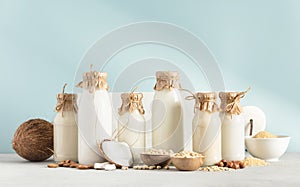 Vegan non dairy plant based milk in bottles on blue background. Alternative lactose free milk substitute, banner