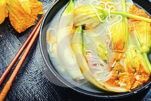 Vegan noodle soup with zucchini flowers