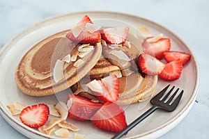 Vegan pancakes with strawberries, nut butter, coconut chips and syrup