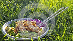 Vegan poke bowl, Hawaiian dish, with chopsticks in the grass
