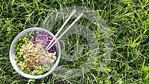Vegan poke bowl, Hawaiian dish, with chopsticks in the grass