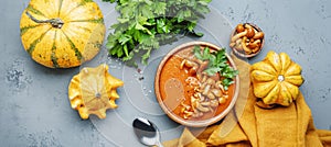 Vegan pumpkin soup puree with mushrooms, pepper and parsley. Winter or autumn healthy vegetarian slow food. Ceramic bowl on gray