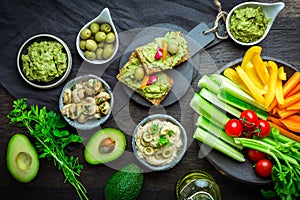 Vegan raw food snacks with fresh juicy vegetables, avocado dip, humus