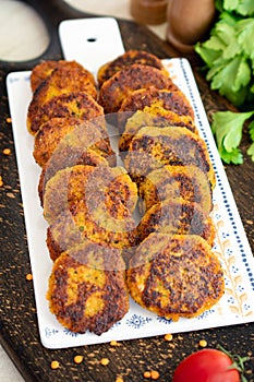 Vegan red lentil patties or burger on a white plate, dark wooden background, vertical