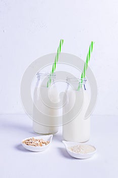 Vegan rice and oat milk with green straws in glass bottles