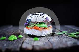 Vegan sushi burger with carrot lox, avocado, cucumber, daikon sprouts and Japanese rice