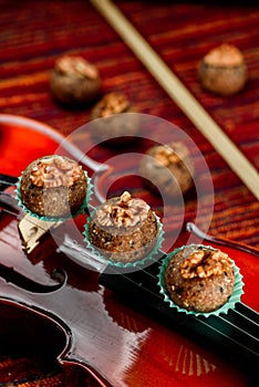 Vegan sweets, Raw food nutty sweets decorated walnut on a beautiful red violin close-up. Healthy sweets