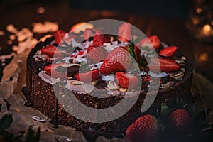 Vegan and tasty chocolate cake with strawberries, cocnut shovel and raspberry seeds, served on a paper serviette