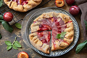 Vegan vegetarian dessert, plums galette with almonds. Healthy homemade wholegrain fruit pie, sweet crostata on a rustic table