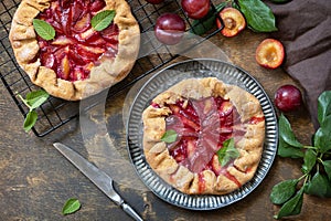 Vegan vegetarian dessert, plums galette with almonds. Healthy homemade wholegrain fruit pie, sweet crostata on a rustic table.