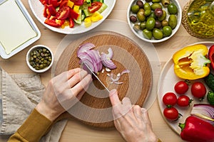 Vegan vegetarian food. Chopping onion, cutting vegetables for greek salad horiatiki. photo