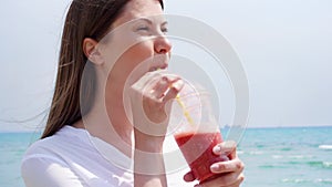 Vegan woman with strawberry smoothie against sea in slow motion. Fit female enjoy healthy lifestyle