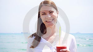 Vegan woman with strawberry smoothie against sea in slow motion. Fit female enjoy healthy lifestyle