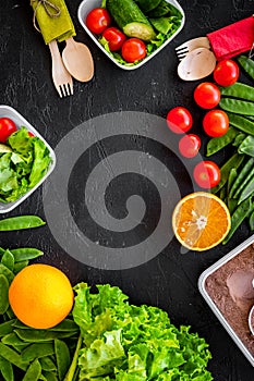 Vegearian lunch. Vegetables tomato, cucumber, asparagus, salad, orange on black background top view copyspace