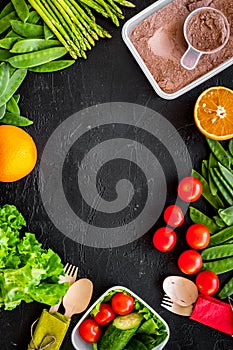 Vegearian lunch. Vegetables tomato, cucumber, asparagus, salad, orange on black background top view copyspace