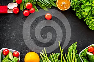 Vegearian lunch. Vegetables tomato, cucumber, asparagus, salad, orange on black background top view copyspace