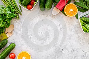 Vegearian lunch. Vegetables tomato, cucumber, asparagus, salad, orange on grey background top view copyspace