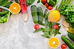 Vegearian lunch. Vegetables tomato, cucumber, asparagus, salad, orange on grey background top view copyspace