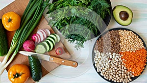 Vegen food on a light background, fresh vegetables and cereals on a plate and plate with herbs top view