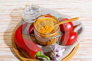 Vegetable caviar, diet puree of pumpkin and zucchini bright orange with pepper, tomatoes, garlic and spices in a glass jar.