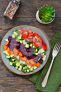 Vegetable cobs salad with stamates, cucumber, pepper, spinach and olive sauce on a wooden background. Salad is a rainbow