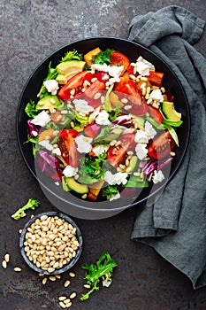 Vegetable dish, salad with avocado, pepper, tomato, italian mix, fresh lettuce, feta cheese and pine nuts. Healthy food