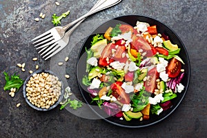 Vegetable dish, salad with avocado, pepper, tomato, italian mix, fresh lettuce, feta cheese and pine nuts. Healthy food