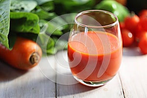 Vegetable juice poured into a glass with green and yellow vegetables