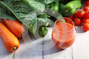 Vegetable juice poured into a glass with green and yellow vegetables