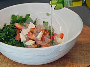 Vegetable lettuce salad. Olive oil pouring into bowl of salad.