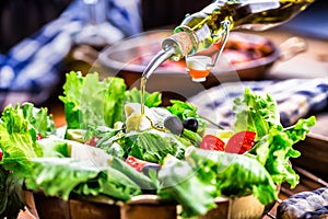 Vegetable lettuce salad. Olive oil pouring into bowl of salad. Italian Mediterranean or Greek cuisine. Vegetarian vegan food