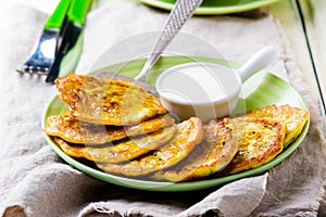 Vegetable marrows fritters with sour cream on a green plate.