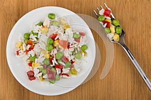 Vegetable mix on plate and fork on wooden table