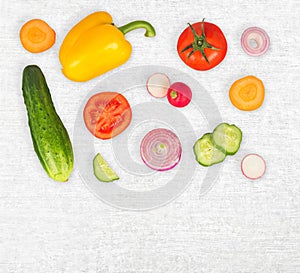 Vegetable mix on white wooden isolated background. Fresh yellow pepper, chopped tomatoes, onion, cucumber slice, carrot, radish.