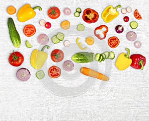 Vegetable mix on white wooden isolated background. Fresh yellow pepper, chopped tomatoes, onion, cucumber slice, carrot, radish.