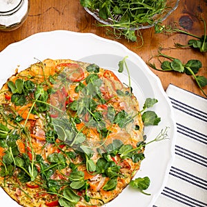 Vegetable omelette with pea shoots microgreens on white plate