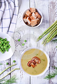 Vegetable pureed soup with asparagus and peas topped with roasted champignons