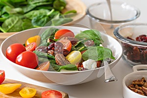 Vegetable salad in a bowl close up. Baby spinach salad with tomatoes, cranberries, pecans, blue cheese and raspberry vinaigrette