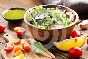 Vegetable salad in bowl and ingredients on wooden table