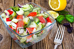 Vegetable salad with crab sticks in glass salad bowl on wooden table