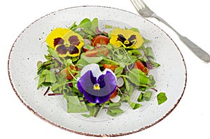 Vegetable salad with edible flowers on white background
