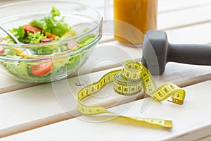 Vegetable salad and fruit smoothies and dumbbell lie on a white windowsill. Concept of healthy lifestyle physical